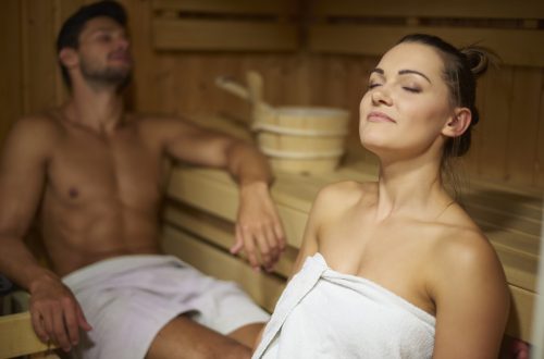 kobieta i mężczyzna siedzący w saunie fińskiej nago w ręcznikach