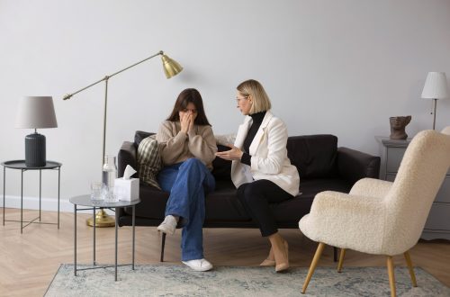 2 kobiety rozmawiające na kanapie, wyglądające na terapeutę i pacjenta